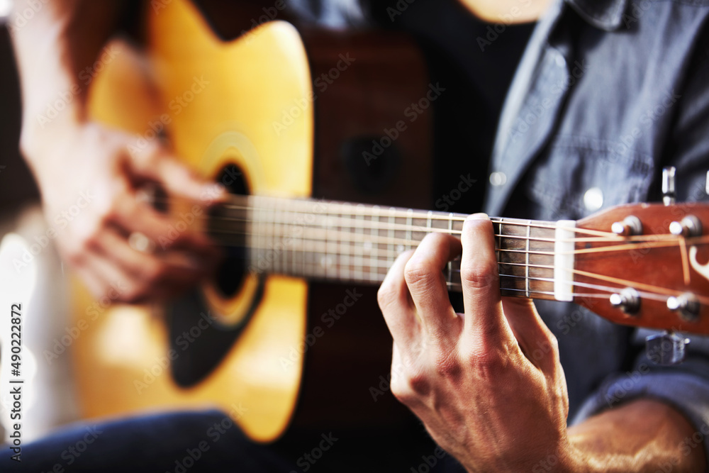 His skill has been gained through hours of practice. Cropped view of masculine hands strumming a gui