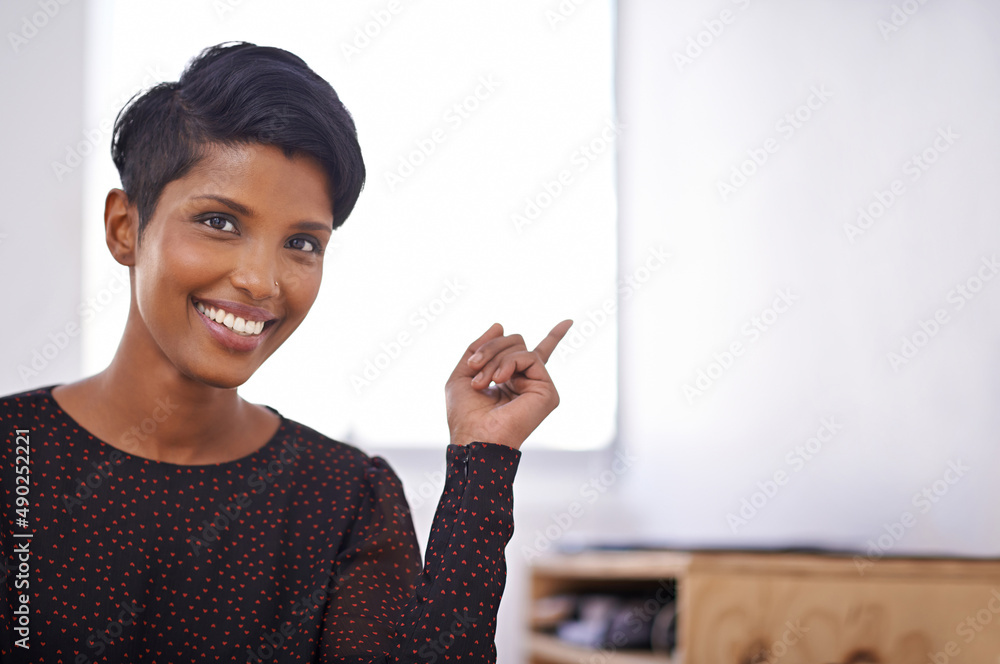 I have an idea. A portrait of a beautiful young woman sitting and pointing in an office.