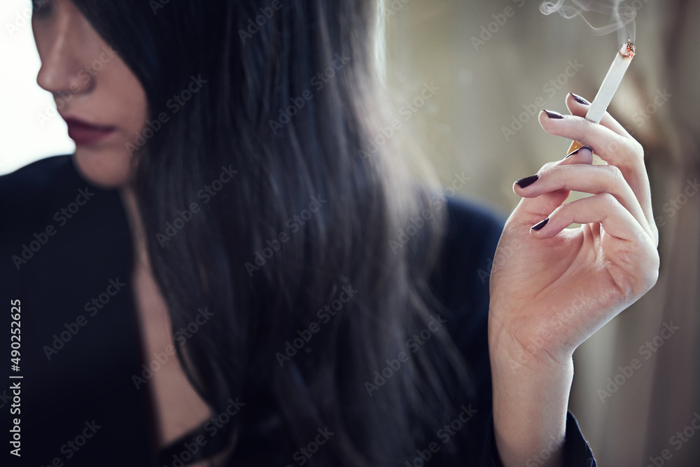 Dark and mysterious. Cropped shot of an elegant young woman smoking.