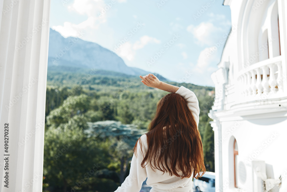 美丽的女人从阳台上看美丽的风景山景