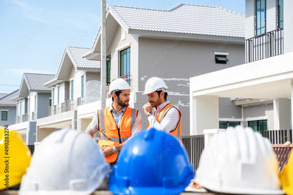 穿着安全背心的专业建筑师在建筑工地讨论他们的工作计划