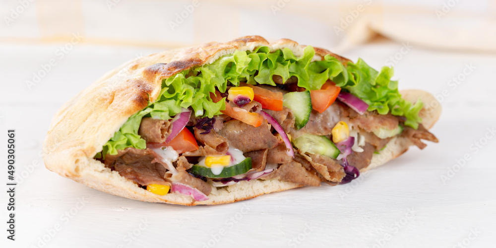 Döner Kebab Doner Kebap slice fast food in flatbread on a wooden board panorama