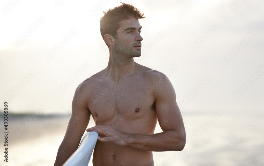 Chasing waves is his passion. A handsome young surfer at the beach craving a good wave.