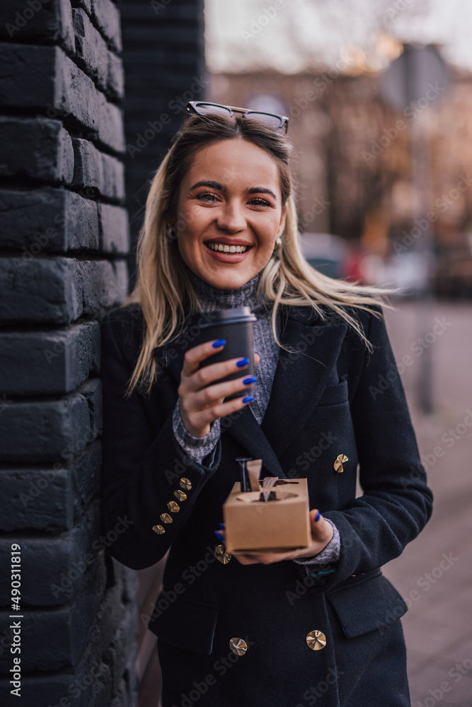 Portrait of caucasian woman with blue nails, holding a cup of coffee, smiling.