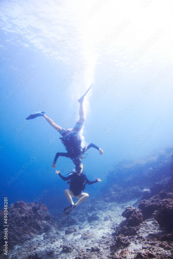 水下探险。两名漂浮的水肺潜水员在水下头对头、颠倒地嬉戏