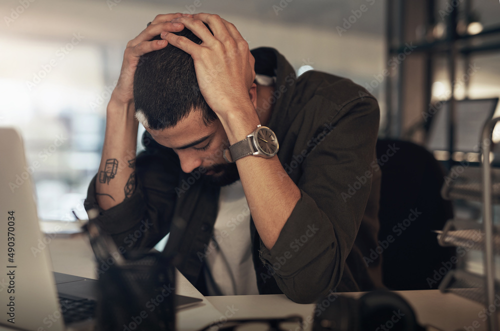 Stress will wear you down if you let it. Shot of a young businessman feeling stressed while working 