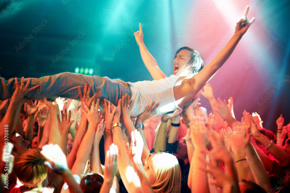 A young man cheering as he crowd surfs at a concert. This concert was created for the sole purpose o