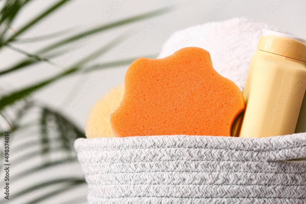 Basket with bottle of cosmetic product and bath sponge, closeup