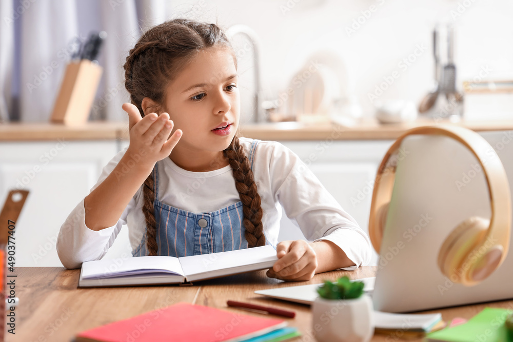 Little girl studying Literature with online tutor at home