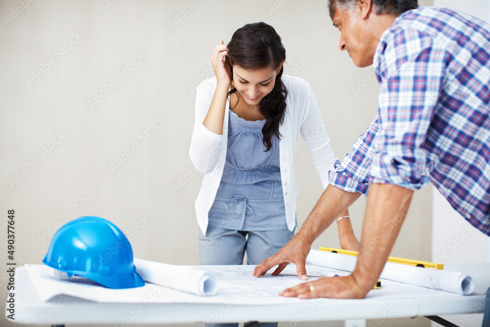 Happy woman discussing with architect over blueprint. Happy young woman smiling while discussing hom