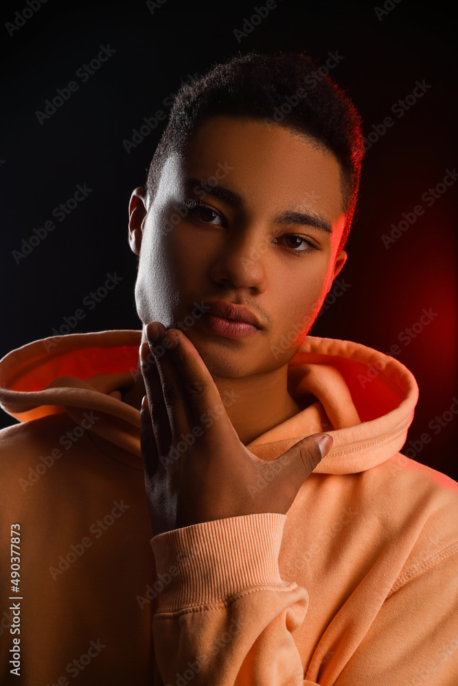 African-American teenage boy in hoodie on black background, closeup