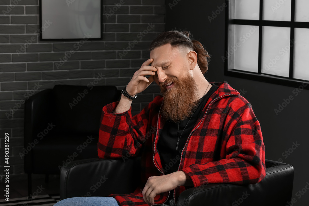 Portrait of sad bearded man sitting in armchair at home