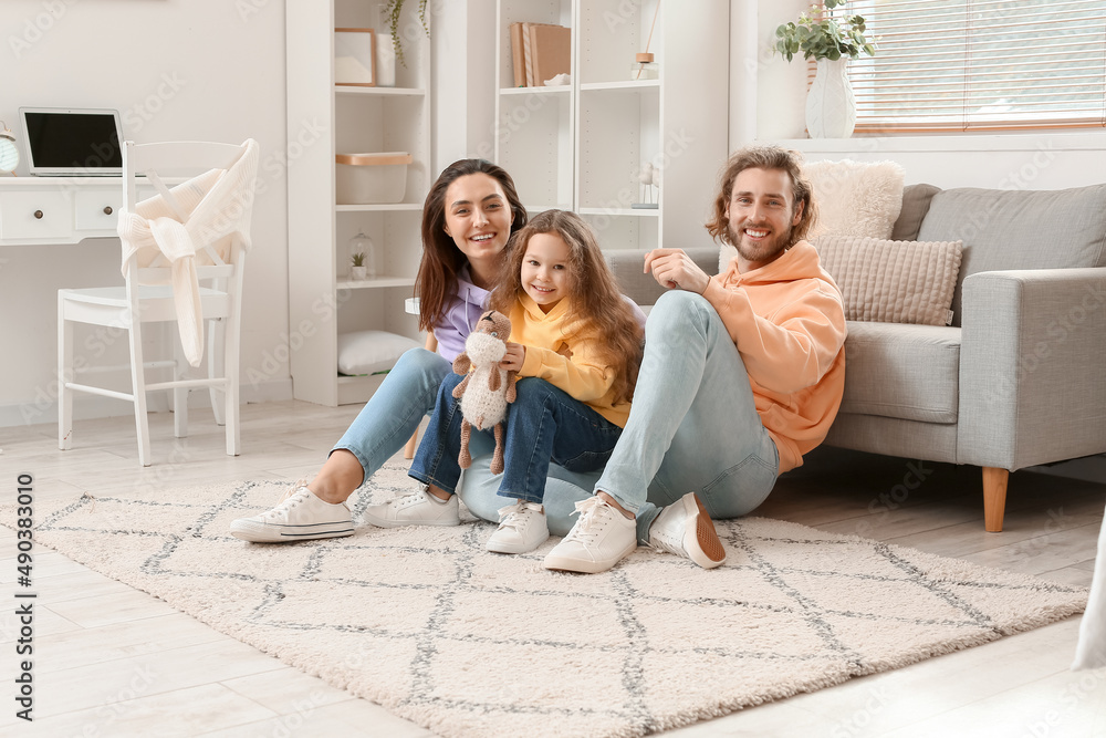 Young family sitting on soft carpet at home