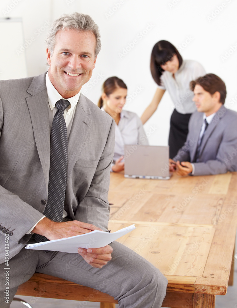 Well-respected business manager. A goodlooking senior business manager holding documents while his t