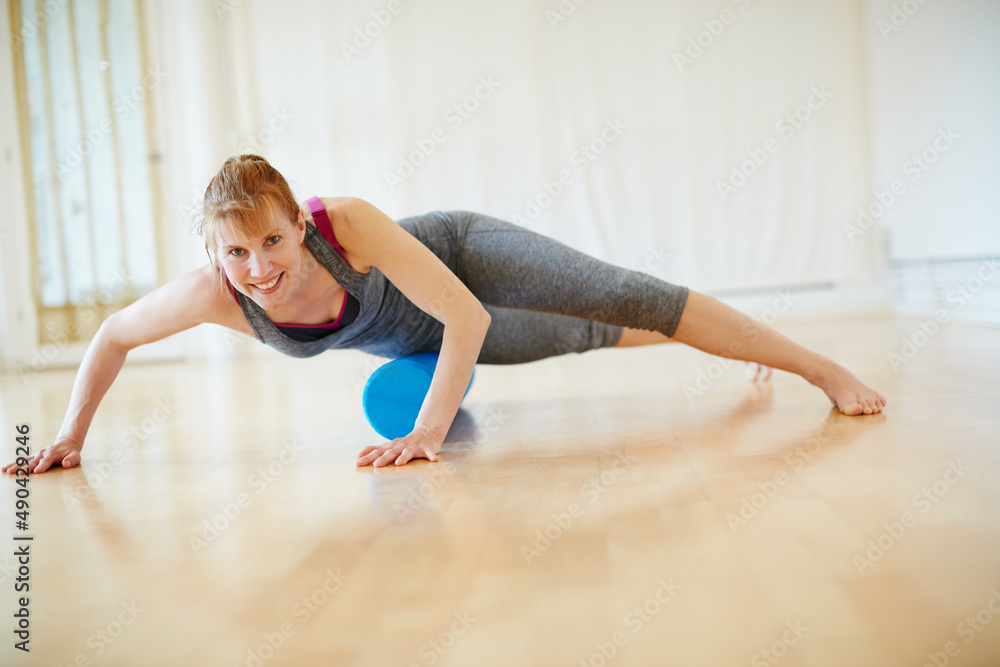 Taking care of her body through yoga. Shot of a woman doing roller foam exercises during a yoga work