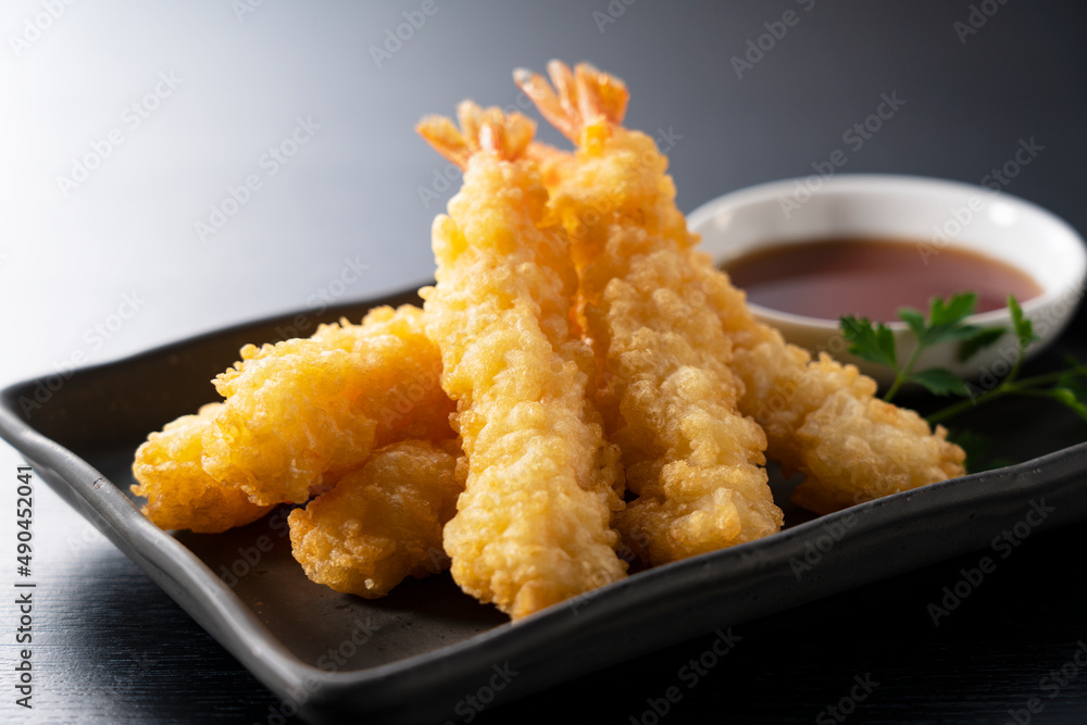 Shrimp tempura on a plate placed against a black background.