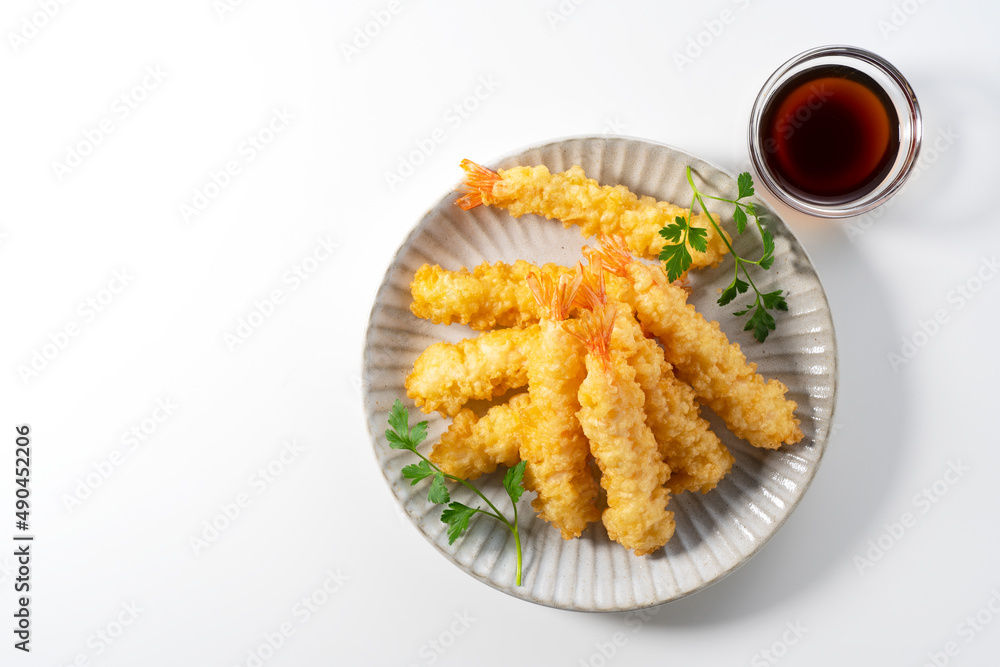 Shrimp tempura on a plate placed on a white background.