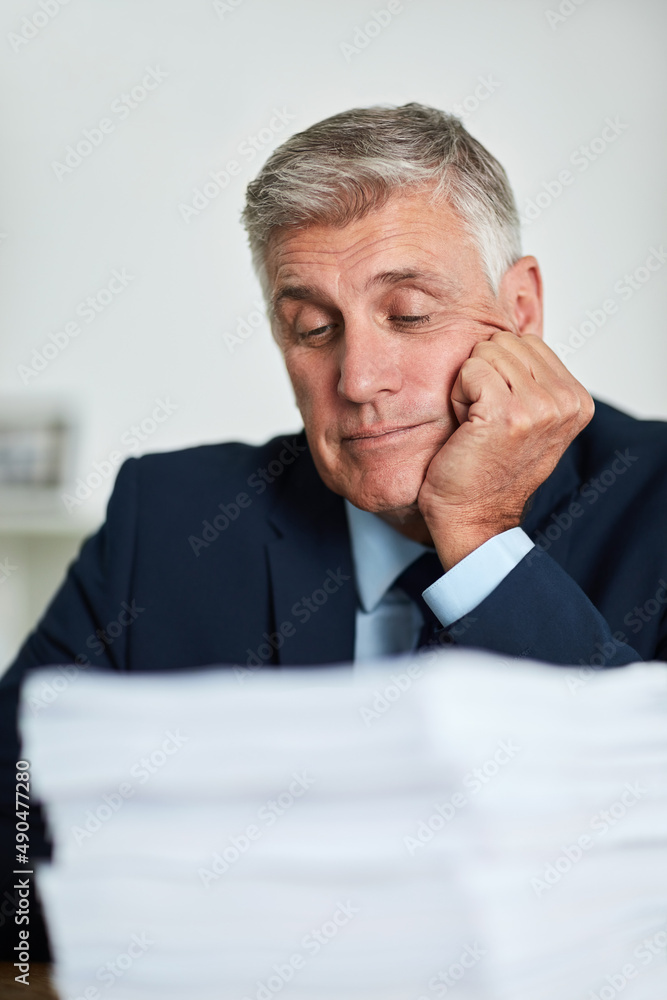 Hes tired of paperwork. Cropped shot of a mature businessman looking bored at work.