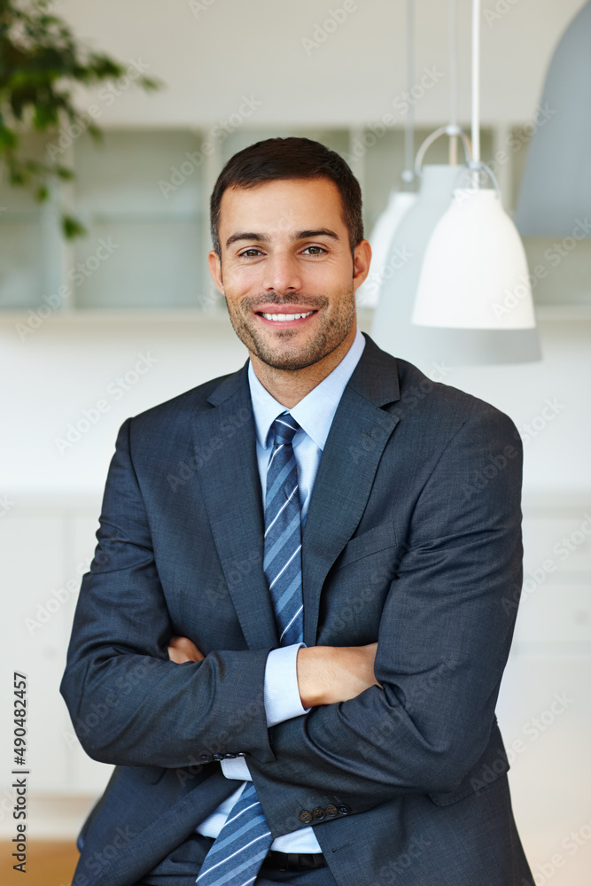 At home in the corporate workplace. Handsome young businessman looking confident with his arms folde