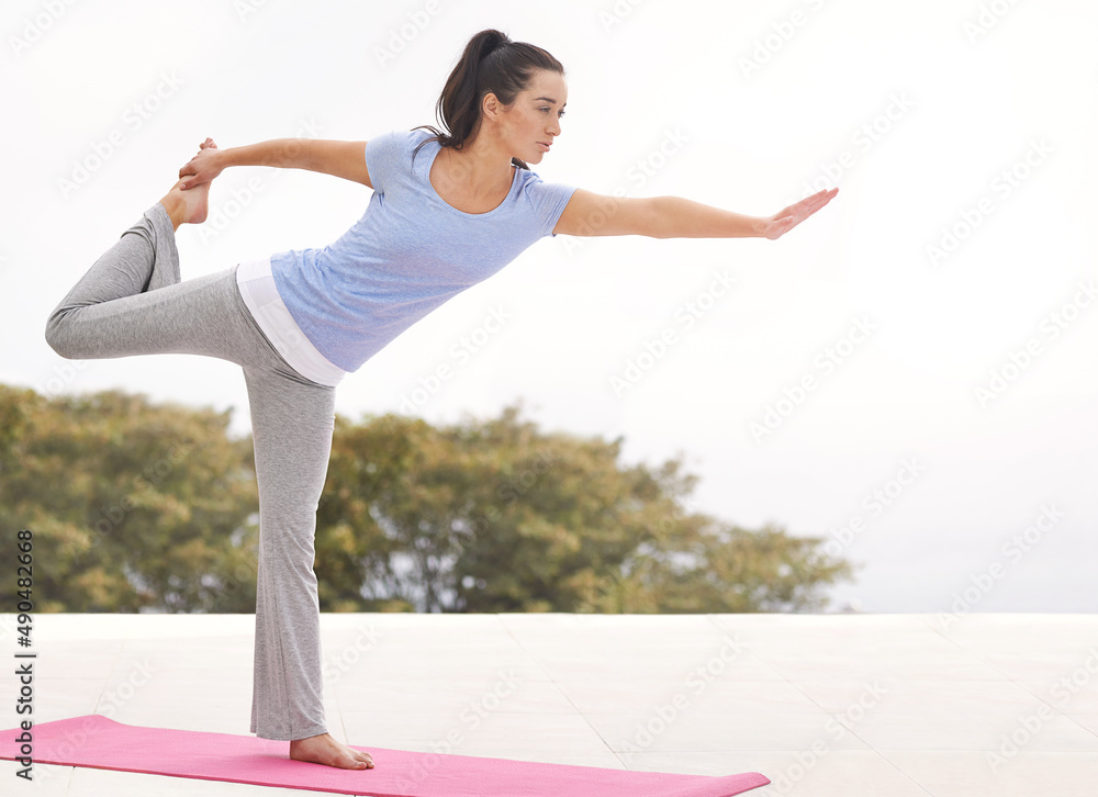 Feeling flexible already. Full length shot of a young woman doing yoga outdoors.