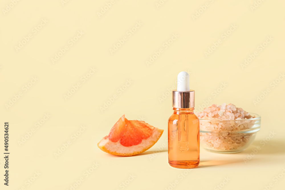 Bottle of essential oil and sea salt on color background