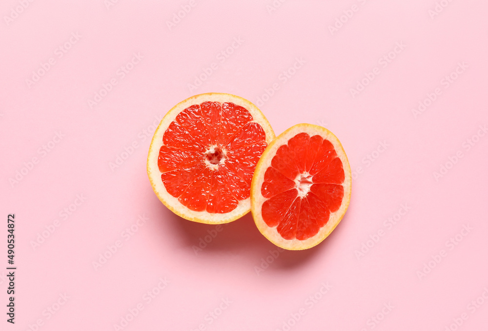 Tasty cut grapefruit on pink background