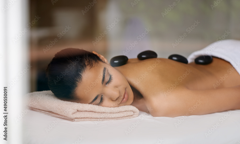 One of lifes little joys. Shot of a young woman enjoying a hot rock treatment at a spa.