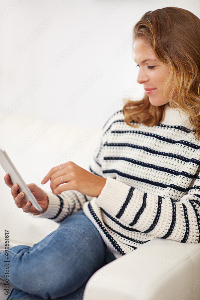 Adding a new entry to her microblog. Shot of a young woman using her digital tablet at home.