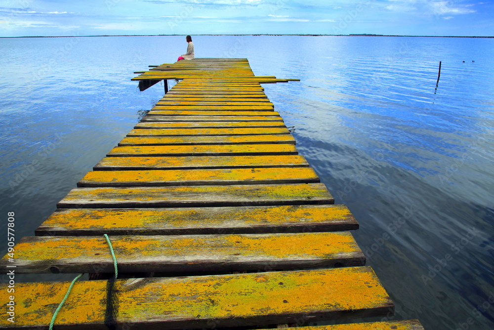 Photographie de Michel Rauscher femme assise sur un ponton jaune à lEtang de Thau dans lHérault en