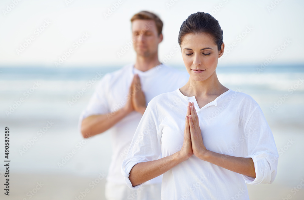 Seaside yoga. A young couple practising yoga on the beach.