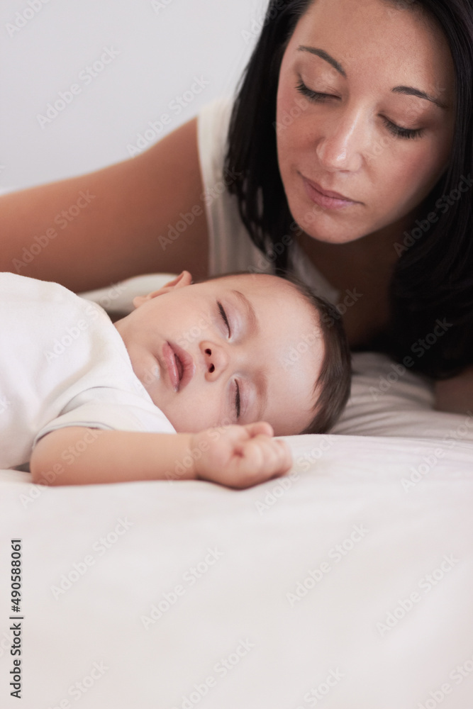 Hes so peaceful. A mother looking lovingly at her baby boy while he sleeps.