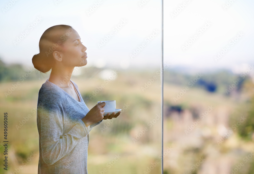 Enjoying a warm cup of coffee while surrounded by nature. Thorugh the window shot of a young woman d