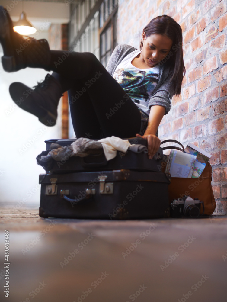 Traveling light just isnt her thing.... A young woman trying in vain to close an over-full suitcase.