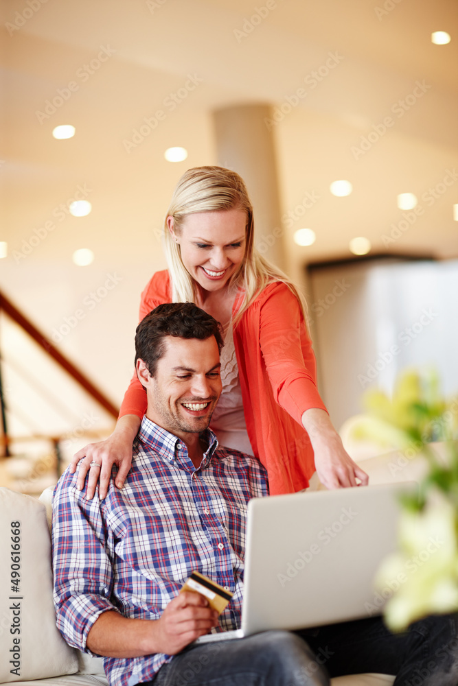 Shopping online with ease. A handsome man sitting on the couch with his laptop holding a credit card