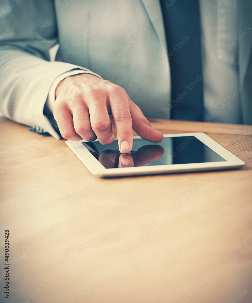 Taking notes on his digital tablet. Cropped shot of a businessman using a digital tablet during a me