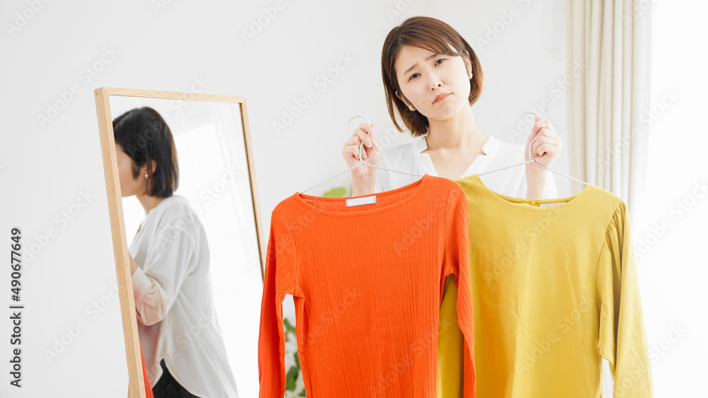 鏡の前で服選びをしている若い女性　ファッションイメージ