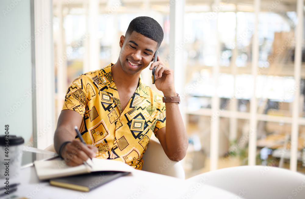 Sure, Ill make a note of that. Shot of a young businessman writing notes while talking on a cellphon