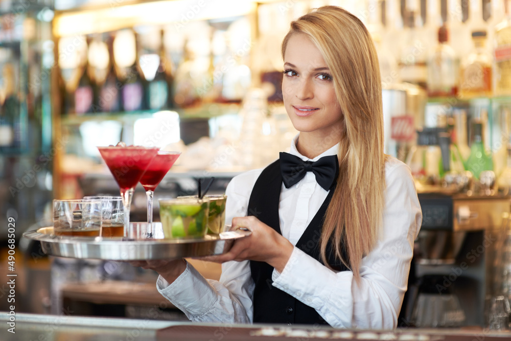 Cocktails for two. Attractive young woman working as a bartender holding a tray of cocktails.