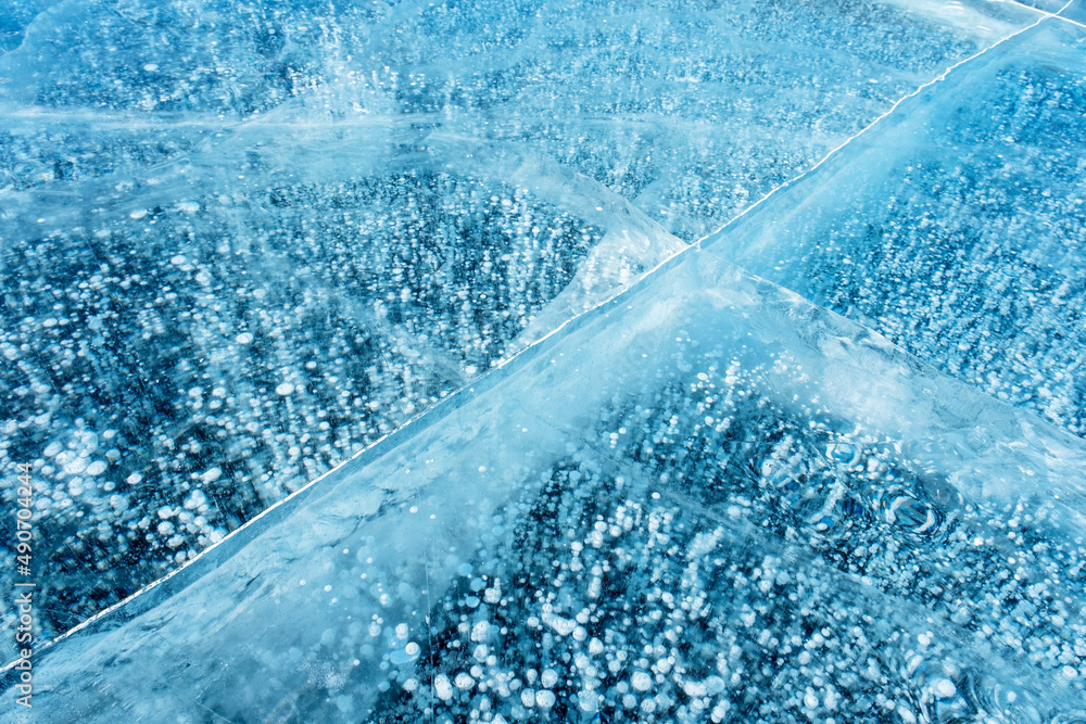 Beautiful transparent blue ice and frozen methane bubbles on Baikal Lake background texture