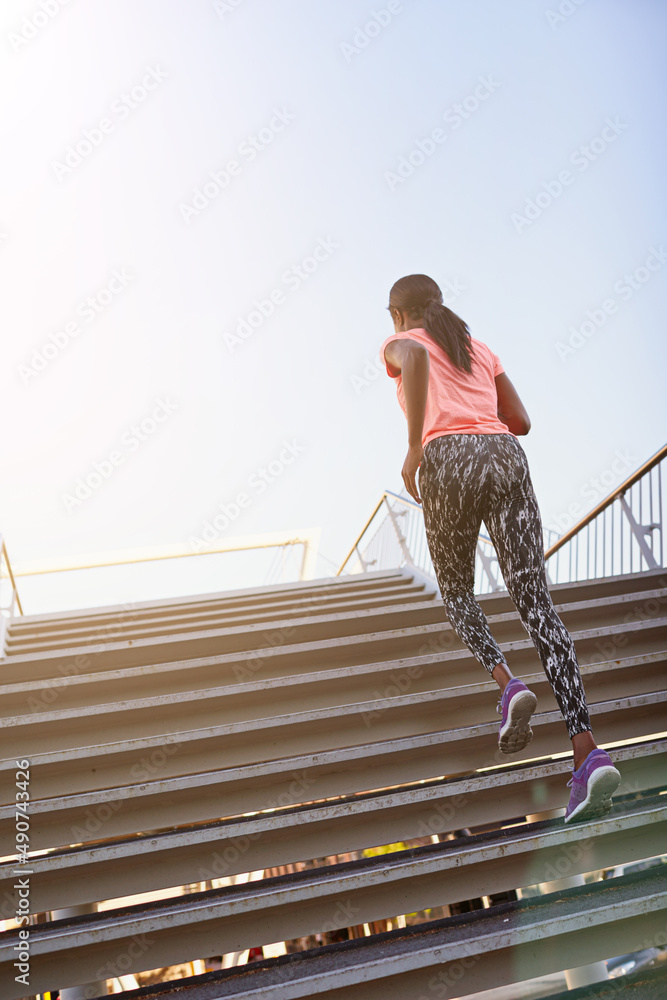 Doing her Rocky impression. Rearview shot of a young female athlete running up and down the bleacher