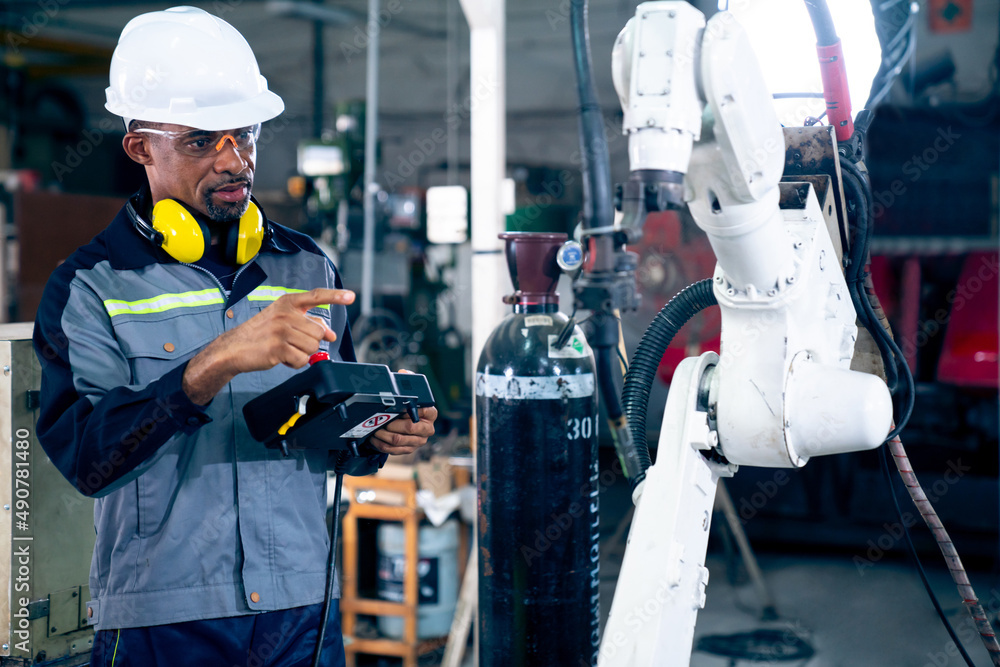 African American factory worker working with adept robotic arm in a workshop . Industry robot progra