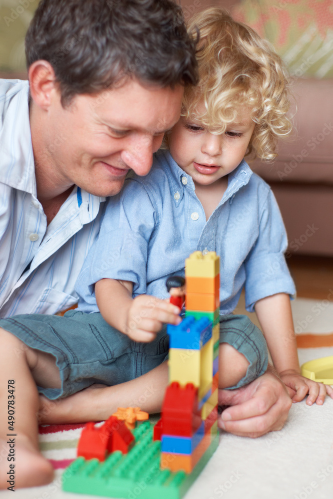 Hes a brilliant builder just like his dad. A father watching his toddler son playing with building b