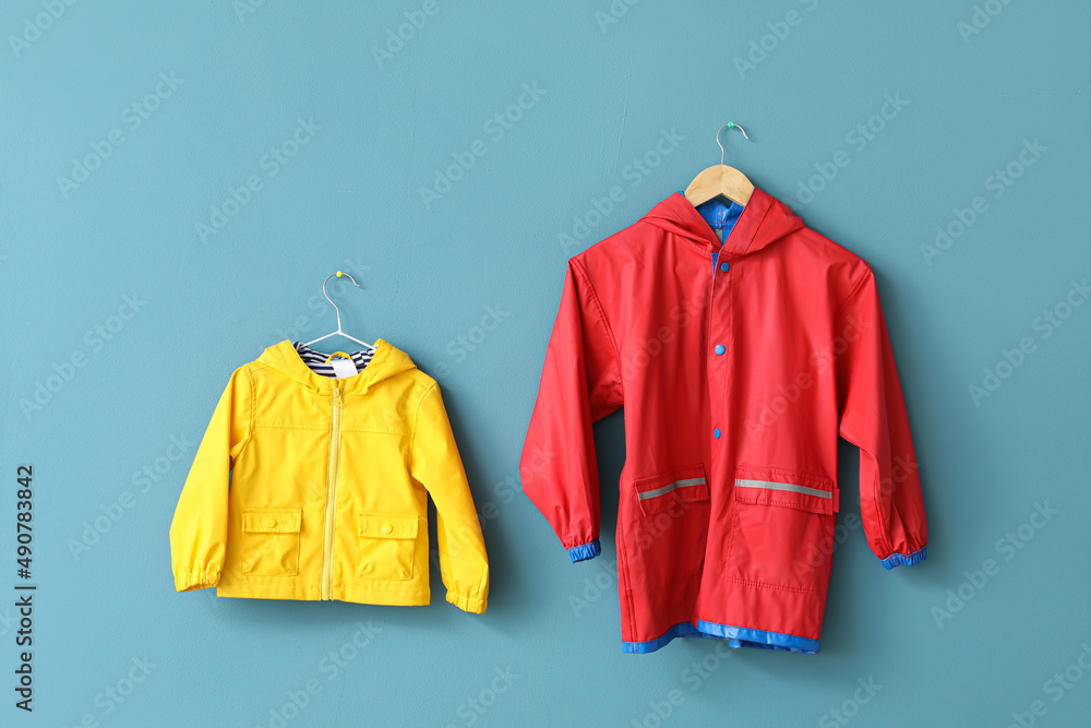 Childs raincoats hanging on blue wall