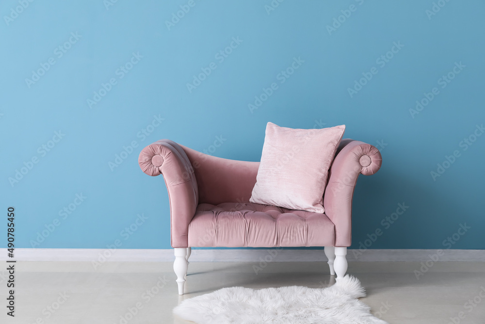 Stylish pink sofa near blue wall