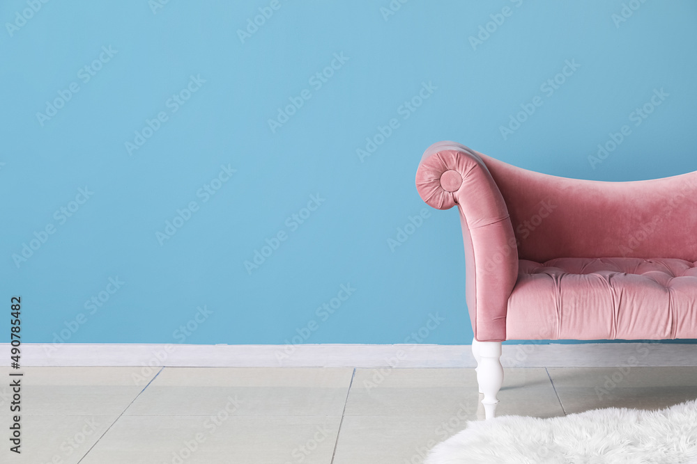 Stylish pink sofa near blue wall