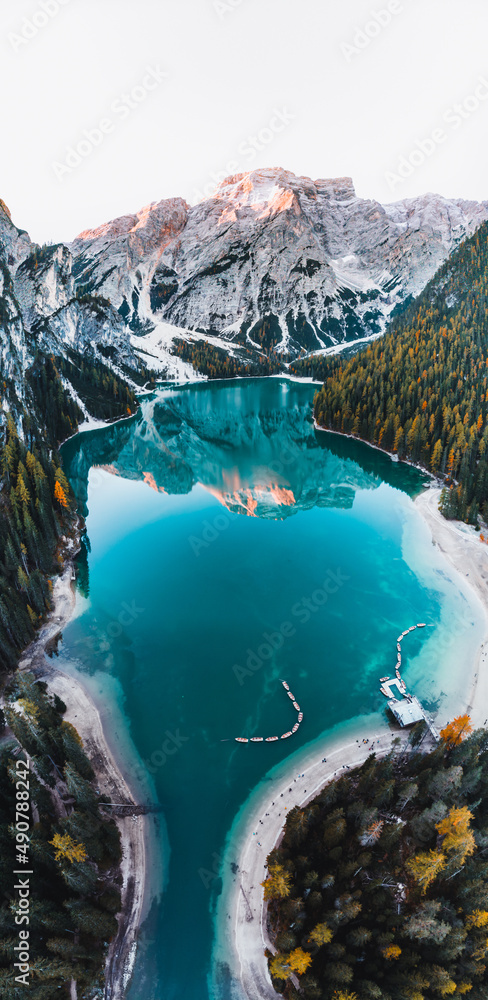 Beautiful lake with azure water with moored boats surrounded by the Dolomites mountains