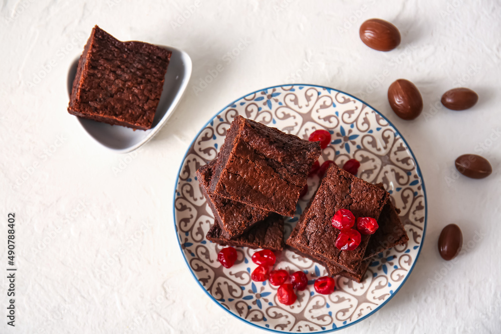 Plate with pieces of delicious chocolate brownie on light background