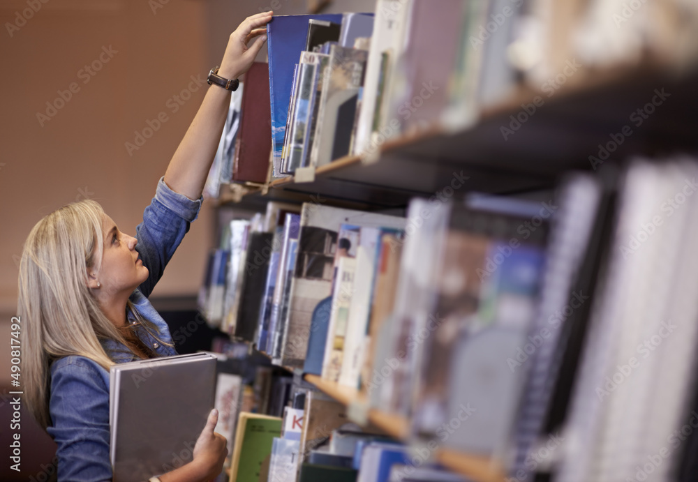 Making use of the campus library. Shot of a young college student in a library.