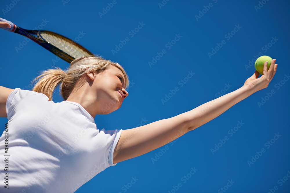 Acing her opponent. A young tennis player serving during a match.