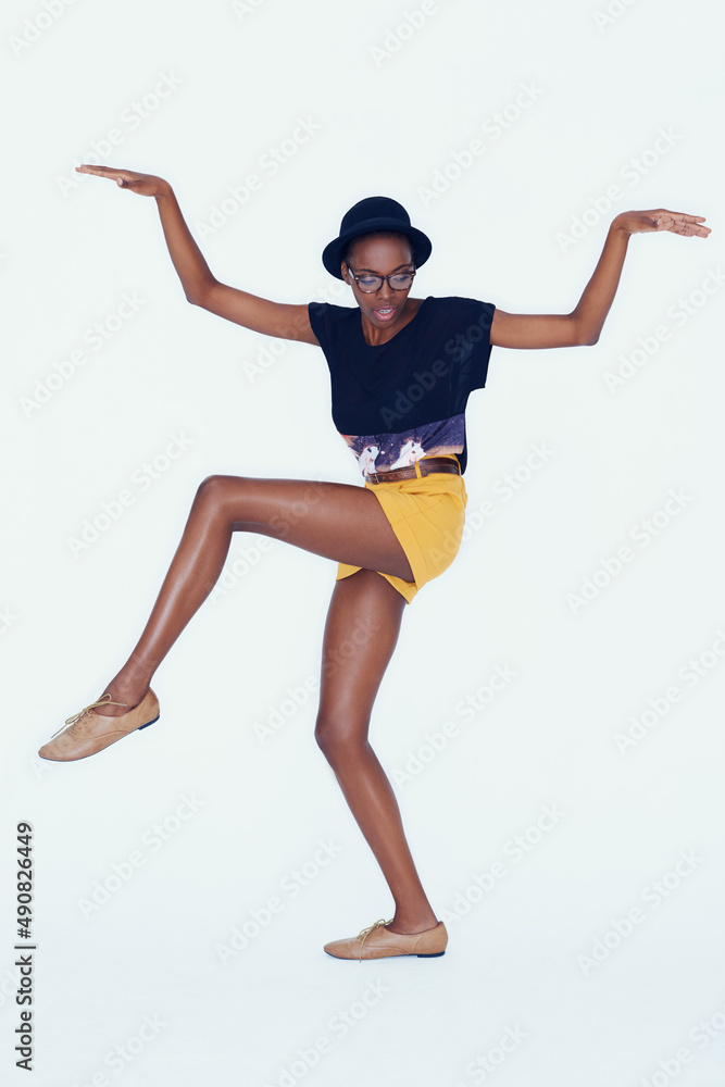 Shes hip and happening. Studio shot of a young ethnic hipster balancing on one leg with her arms rai